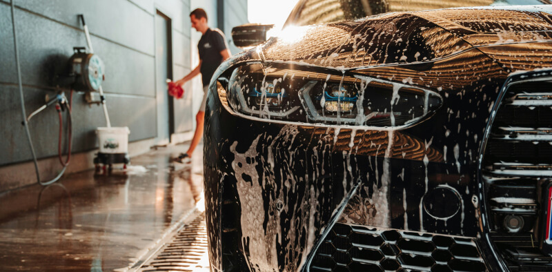 Mann vasker bilen utendørs